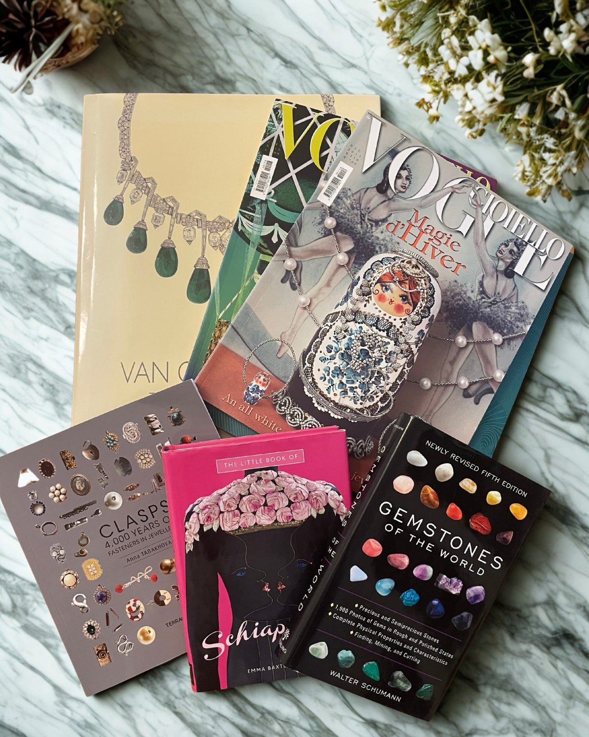 Collection of jewellery books and style on a marble surface with decorative elements.