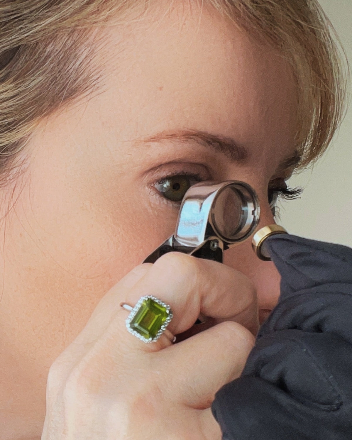 Person examining a jewellery creation with a magnifying glass. Quality Control, made to order, crafted in Italy.