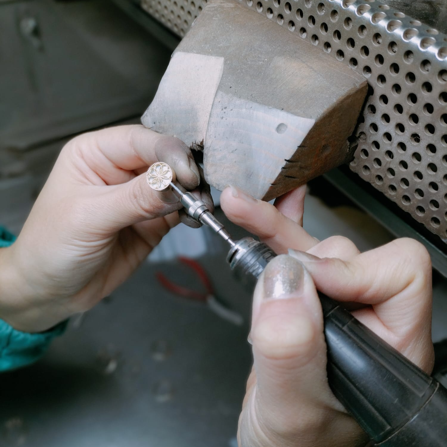 Person using a tool to work on a small earring, with a blurred background. Made to order, crafted in Italy.