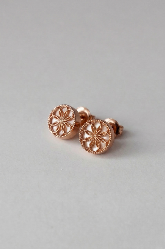 Gold earrings with byzantine inspired designs on a light grey background. The Ravenna white mother of pearl Stud Earrings in 18kt Rose Gold.