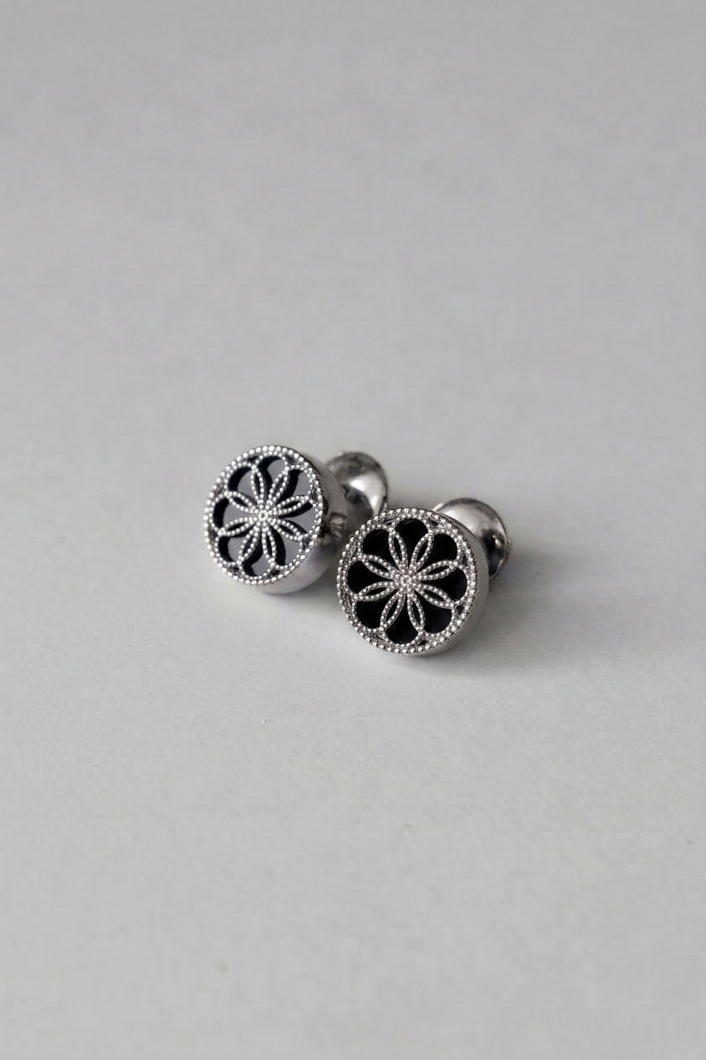 A pair of Gold earrings with a byzantine inspired design. The Ravenna Black Onyx Stud Earrings in 18kt White Gold. 
