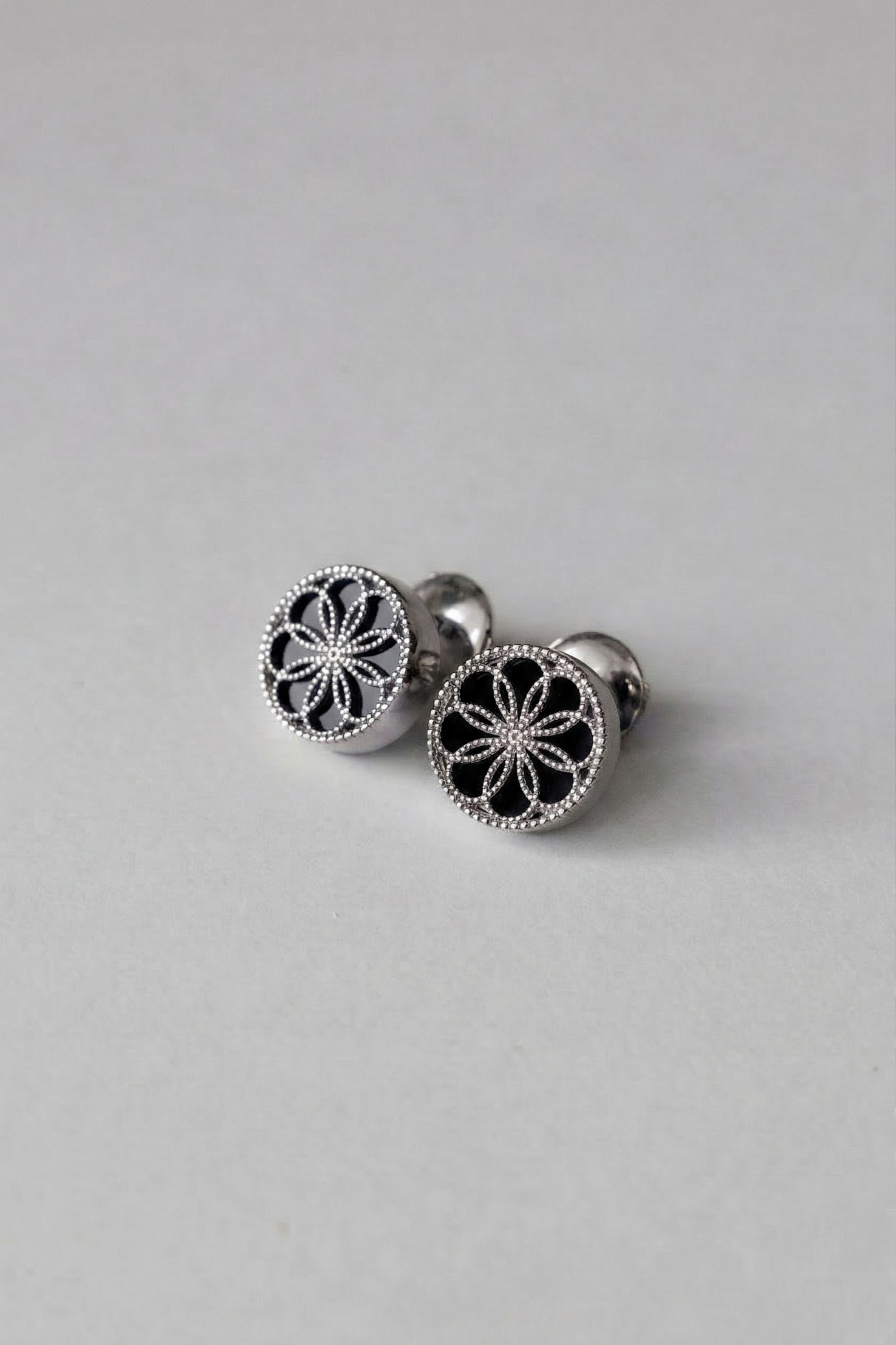 A pair of Gold earrings with a byzantine inspired design. The Ravenna Black Onyx Stud Earrings in 18kt White Gold. 
