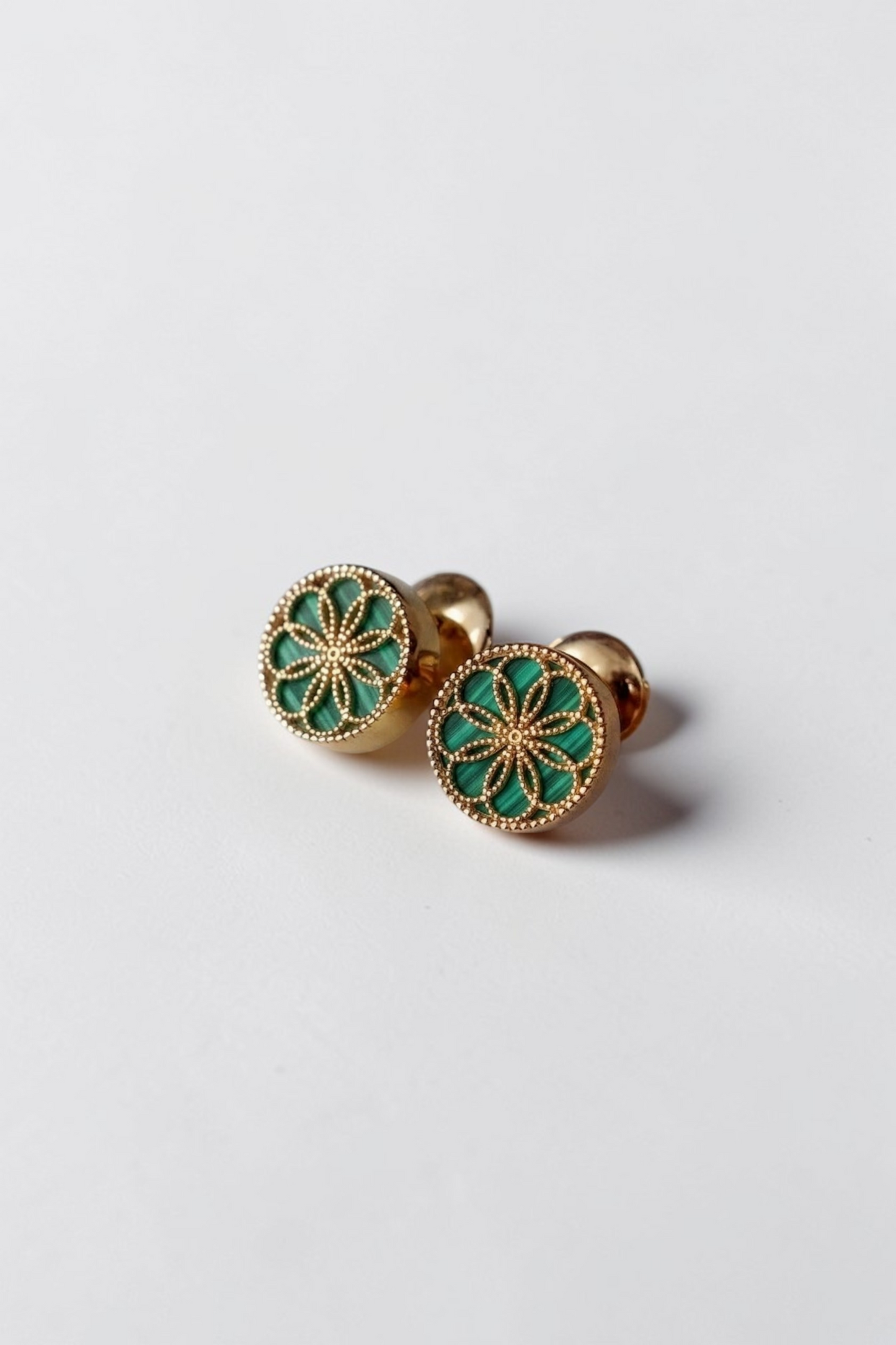 Gold earrings with byzantine inspired designs on a light gray background. The Ravenna Green Malachite Stud Earrings in 18kt Yellow Gold.