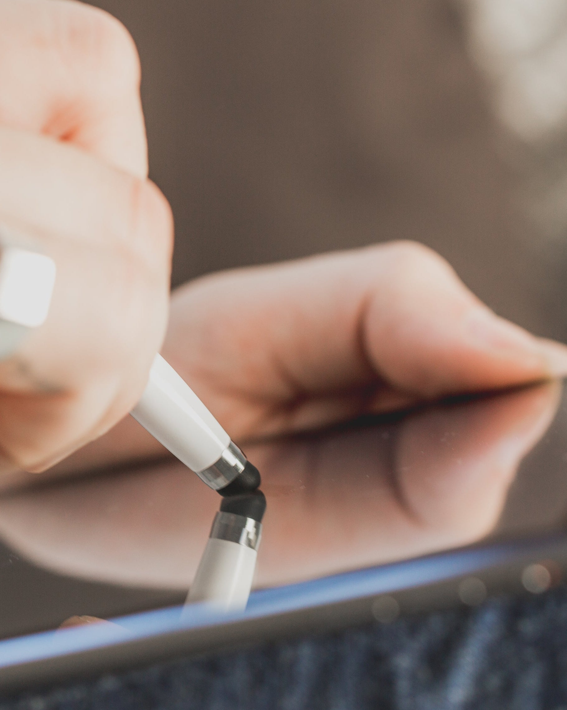 Close-up of a hand holding a white electronic device with a blurred background. Interpretating the design requests.