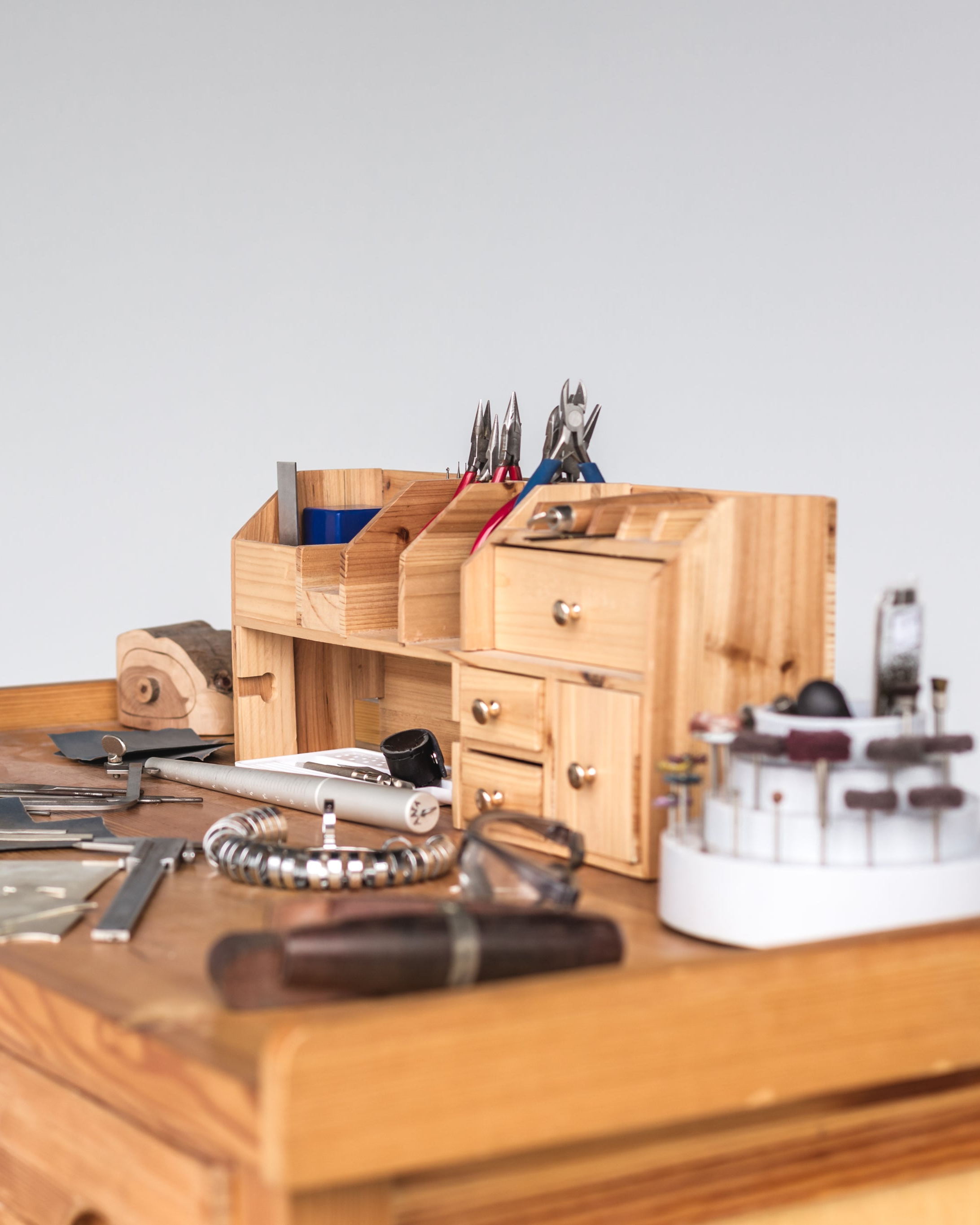 Wooden desk organizer with various goldsmith tools and items on a wooden surface. Made in Valenza, Made in Italy. Italian craftsmanship.
